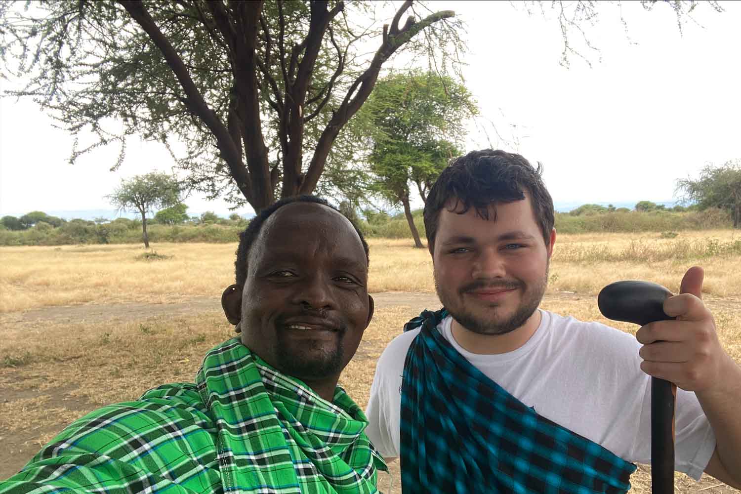 Student standing with man in front of tree