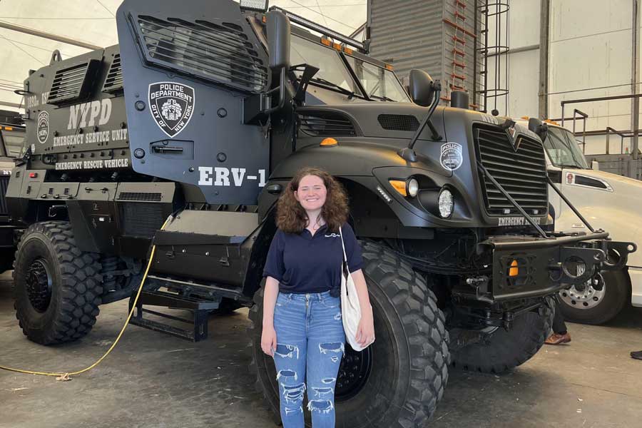 Student standing in front of a police vehicle