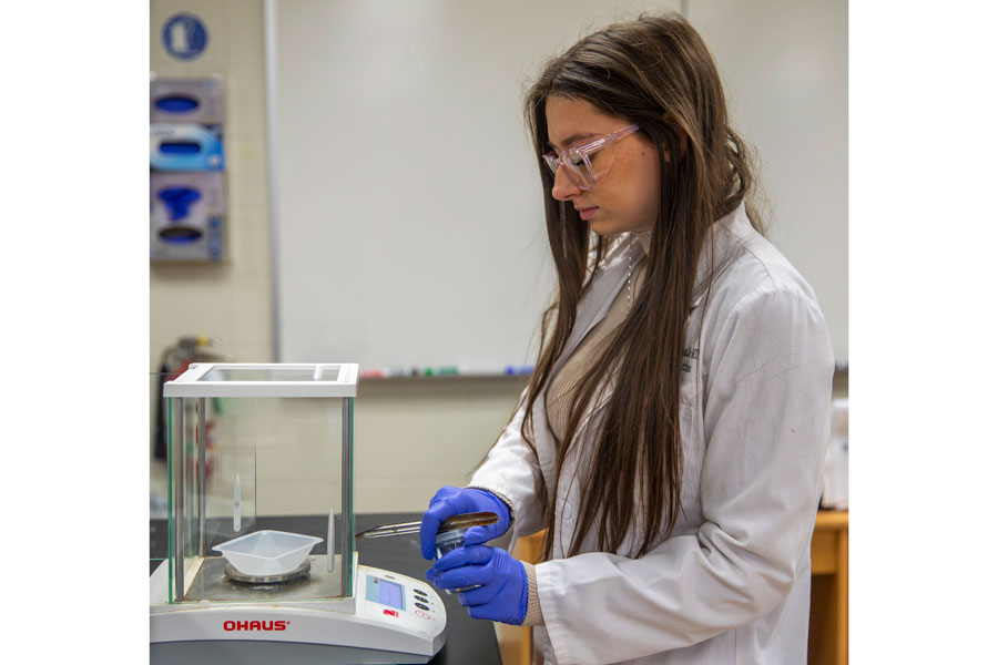 Gabriella working in the lab with a beaker and other equipment