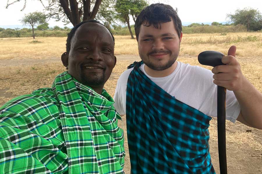 Student standing with man in front of tree