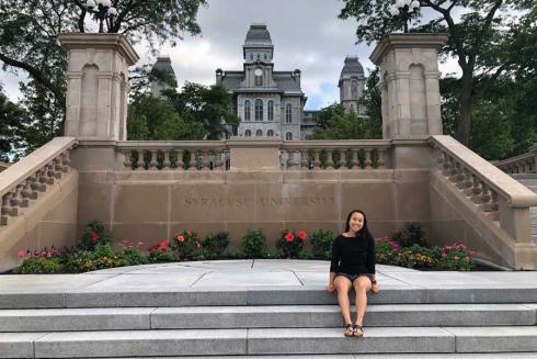 Graduate in front of Syracuse University